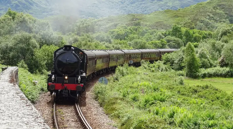 Jacobite steam train winding along the West Highland Line through green hills
