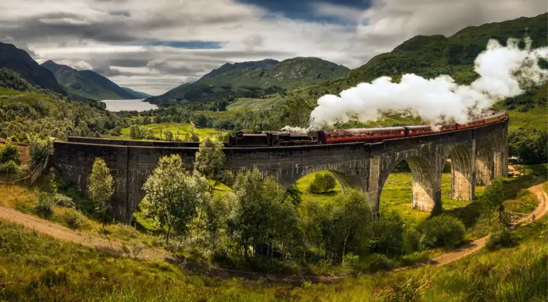 Jacobite steam train crossing the Glenfinnan Viaduct with Loch Shiel beyond