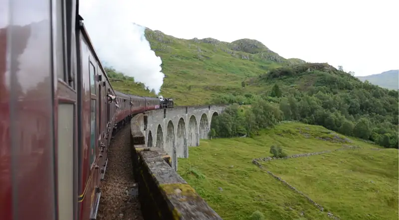 Onboard view along the maroon carriages of the Jacobite rounding the Glenfinnan Viaduct